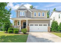 Charming two-story home featuring a manicured lawn, stone accents, and a spacious two-car garage at 744 Birch Arbor Cir, Raleigh, NC 27604