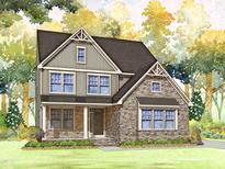 Charming two-story home with stone accents, gray siding, and a well-manicured lawn with trees in the background at Lot 17 Magnolia Acres Ln, Fuquay Varina, NC 27526
