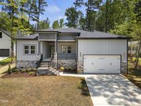 Charming home featuring stone accents, a two-car garage, and a welcoming front porch at 107 Mohave Dr, Louisburg, NC 27549