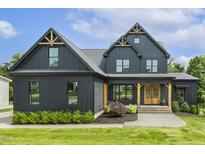 Stunning modern farmhouse with dark siding, gabled roofs, and manicured lawn at 1141 Duke Farm Dr, Wake Forest, NC 27587
