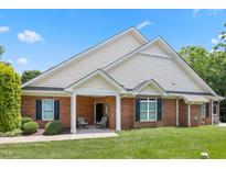 Charming brick home featuring a cozy front porch and well-maintained landscaping under a clear blue sky at 127 Bobwhite Way, Mebane, NC 27302