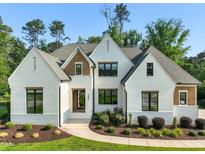 Charming two-story home featuring white brick, black framed windows, manicured landscaping, and a concrete walkway at 1409 Montvale Ridge Dr, Cary, NC 27519