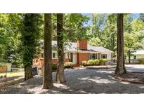Charming brick home featuring mature trees, well-maintained landscaping, and a welcoming front entrance at 2005 Cole Mill Rd, Durham, NC 27712