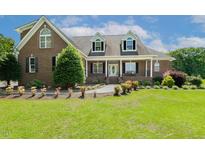 Charming two-story brick home with a manicured lawn and inviting front porch at 206 W Stoneybrook Ct, Benson, NC 27504