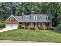 Charming brick home with dormer windows, two-car garage, and a well-manicured lawn at 2204 Basil Drive, Raleigh, NC 27612