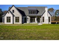 Stunning exterior of a home with stone accents, a gray roof, a front porch, and manicured green lawn at 236 Gaines Trail, Pittsboro, NC 27312