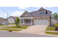 Charming brick home featuring an attached two car garage, covered porch, and manicured lawn at 3020 High Plains Dr, Fuquay Varina, NC 27526