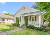 Charming home featuring a manicured lawn, brick walkway, and covered porch with white railing and green accents at 307 W Austin St, Mebane, NC 27302