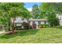 Charming two-story home with a lush green lawn, mature trees, and well-manicured shrubs at 3308 Cobblestone Court Ct, Raleigh, NC 27607