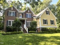 Charming two-story home featuring brick and yellow siding with black shutters, surrounded by lush greenery at 3650 Pleasants Ridge Dr, Wake Forest, NC 27587
