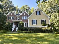 Two-story home with brick and siding, dark shutters, white railing, and landscaped yard surrounded by mature trees at 3650 Pleasants Ridge Dr, Wake Forest, NC 27587