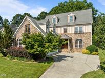 Beautiful stone home featuring dormer windows and a spacious driveway surrounded by lush landscaping at 4913 Great Meadows Ct, Raleigh, NC 27609