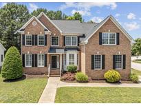 Charming two-story brick home featuring a landscaped yard, black shutters, and a welcoming entrance at 712 Brittley Way, Apex, NC 27502