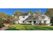 Charming two-story home featuring a well-manicured lawn, mature trees, and a welcoming front porch at 1004 E Willowbrook Dr, Burlington, NC 27215