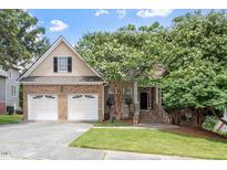 Charming brick and siding home with a two-car garage, lush lawn, and mature flowering tree at 1211 E Pointe Dr, Durham, NC 27712