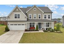 Inviting two-story home with a charming front porch, well-manicured lawn, and attached two-car garage at 200 Cloud Berry Ln, Holly Springs, NC 27540