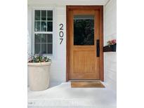Inviting front entrance with a wood door, flower pot, and welcome mat at 207 N Aiken St, Fuquay Varina, NC 27526