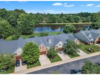 Aerial view of townhomes with a tranquil lake view in a lush, green neighborhood at 240 Meadow Beauty Dr, Apex, NC 27539
