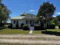 Charming single-story home featuring a green metal roof and well-manicured landscaping at 2657 Joel Johnson Rd, Lillington, NC 27546