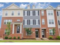 View of three townhomes with brick and gray exteriors, black doors, and manicured lawns on a sunny day at 503 Gateway Townes Blvd, Wake Forest, NC 27587