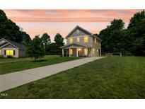 Charming two-story home with covered porch and long driveway on a spacious lawn at 567 E Ridge Ave, Liberty, NC 27298
