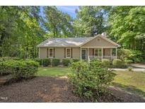 Charming single-story home featuring a cozy front porch and surrounded by mature trees at 6009 Shadow Moss Cir, Raleigh, NC 27603