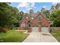 Traditional two-story brick home featuring an attached two-car garage and well-maintained lawn at 7 Teahouse Ct, Durham, NC 27707