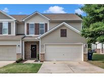 Charming townhome with a two-car garage, neat lawn, and inviting front entrance with brick and black door at 8111 Yaxley Hall Dr, Raleigh, NC 27616