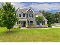 Charming two-story home with stone accents, a well-manicured lawn, and professional landscaping at 8909 Tara Hill Ln, Wake Forest, NC 27587