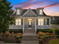 Charming home featuring dormer windows, a welcoming front porch with white columns and manicured landscaping at 1000 Groveview Wynd, Wendell, NC 27591