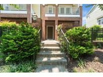 Brick townhouse with a charming front entrance, featuring a garden and a few steps leading up to a brown front door at 1017 Frank Page Dr, Cary, NC 27511
