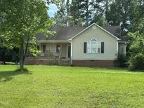 Charming single-story home with a covered front porch and a well-maintained lawn at 104 Holly Ranch Ct, Willow Springs, NC 27592