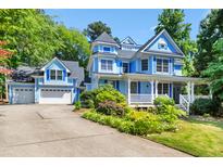 Charming two-story home with light blue siding, white trim, front porch, and an attached two car garage at 104 Shady Ridge Ct, Apex, NC 27502