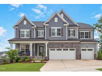 Charming two-story home features a stone facade, gray siding, and a well-manicured lawn at 112 Bellmont Crest Dr, Holly Springs, NC 27540