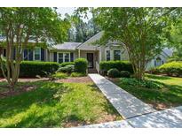 Charming home features a well-manicured front yard with lush greenery and a welcoming walkway to the front door at 115 Heatherwood Dr, Apex, NC 27502
