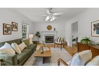 Bright living room featuring a fireplace, ceiling fan, wood floors, and stylish decor at 15 Gray Fox Ct, Durham, NC 27713