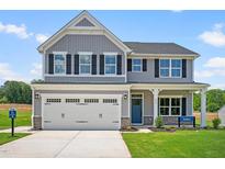 Charming two-story home with gray siding, black shutters, a blue front door, and well-manicured lawn at 210 Bluebell St, Sanford, NC 27330