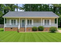 Charming single-story home with a well-manicured lawn, complemented by a cozy front porch and a light blue front door at 212 Southerby Dr, Garner, NC 27529