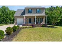 Charming two-story home featuring a well-manicured lawn and a welcoming front porch with rocking chairs at 486 S Denise Ave, Coats, NC 27521