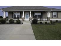 Charming home featuring a covered front porch with inviting rocking chairs and beautifully landscaped front yard at 60 Falling Leaf Ln, Benson, NC 27504