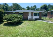 Cozy brick home featuring a well-maintained lawn and mature landscaping, creating a welcoming curb appeal at 916 Waring St, Durham, NC 27704