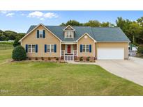 Charming tan house featuring blue shutters, a well-manicured lawn, and an attached two-car garage at 191 Bridle Dr, Angier, NC 27501