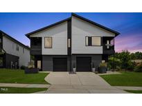 Contemporary two-story duplex featuring clean lines, gray siding, and a double garage at dusk at 2225 Millbank Village Ct # 101, Raleigh, NC 27610