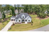 Expansive aerial view of a modern farmhouse with black trim, white exterior, and a lush green lawn at 2328 Sanctuary Dr, Raleigh, NC 27606