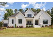 Charming new construction home featuring a modern farmhouse design, white brick, black trim, and a lush front yard at 2328 Sanctuary Dr, Raleigh, NC 27606