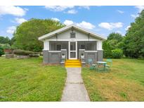 Charming home with a screened-in porch, bright yellow stairs, and a cozy outdoor seating area at 2815 Orange Grove Rd, Hillsborough, NC 27278