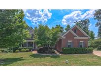 Charming brick home with lush landscaping, mature trees and a well-manicured lawn at 3408 Mount Pisgah Way, Cary, NC 27519