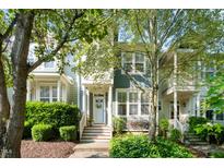 Inviting two-story townhome with a charming front porch, lush greenery, and a well-manicured lawn at 408 Heritage Village Ln, Apex, NC 27502
