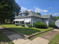 Classic two-story home features a covered front porch, green lawn and mature landscaping at 500 W Main St, Benson, NC 27504
