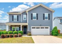 Charming two-story home with blue siding, a front porch, a two-car garage and well-maintained landscaping at 512 Teal Lake Dr, Holly Springs, NC 27540